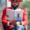 man in red long sleeve shirt holding white book
