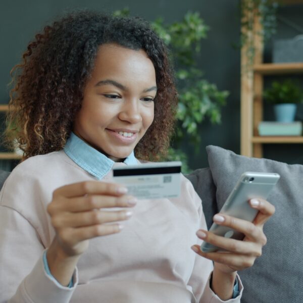 Young woman holding credit card and smartphone.