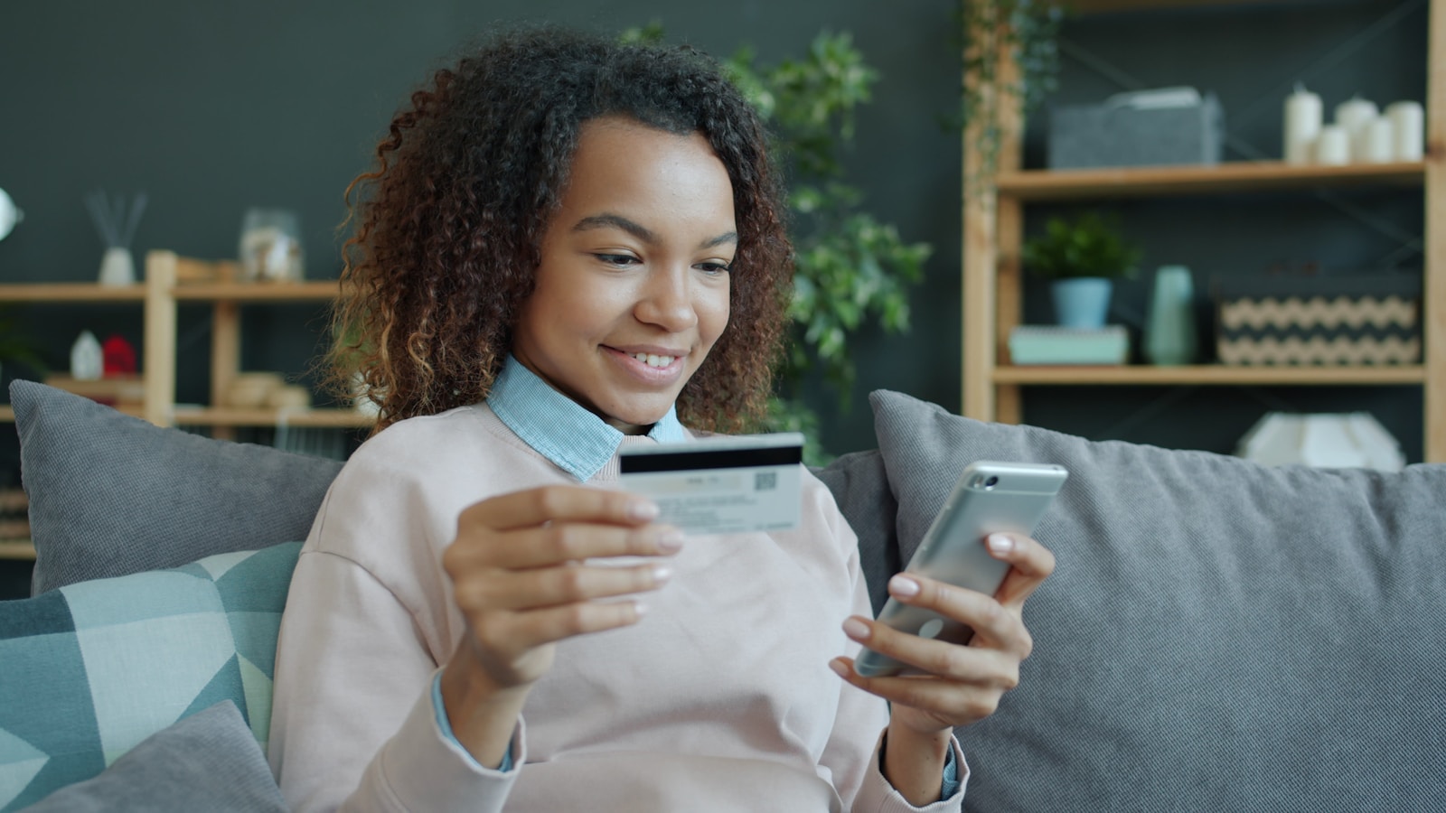 Young woman holding credit card and smartphone.