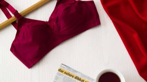 Red bra on hanger, cup of tea, newspaper, and red fabric on a white table for a modern and stylish look.