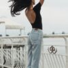 a woman standing on a pier with her hair blowing in the wind