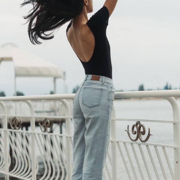 a woman standing on a pier with her hair blowing in the wind