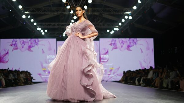 Elegant model in lavender gown showcases high fashion on runway during Indian fashion week event.