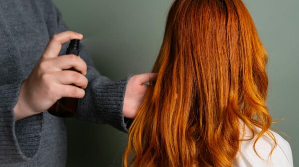 Close-up of hairdresser spraying hair product on long red hair.