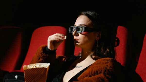 A woman enjoying a cinema experience wearing 3D glasses, holding popcorn.