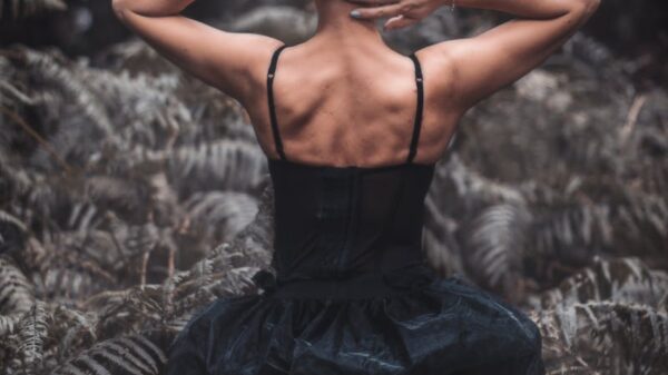 Rear view of a woman in a black dress surrounded by a lush forest atmosphere.