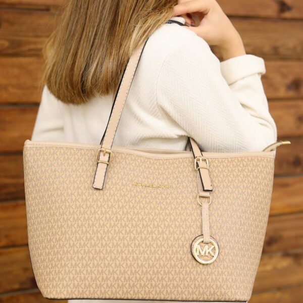 Elegant beige leather tote bag worn by a woman against a wooden backdrop.