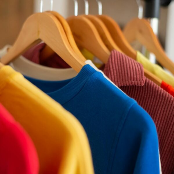 Vibrant clothing displayed on wooden hangers, showcasing fashion and color variety.