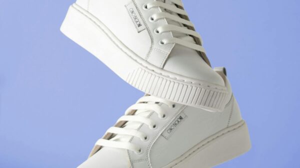 Minimalist white sneakers hanging against a soft blue backdrop for fashion product focus.