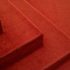 Detailed view of red carpeted stairs, highlighting texture and design.