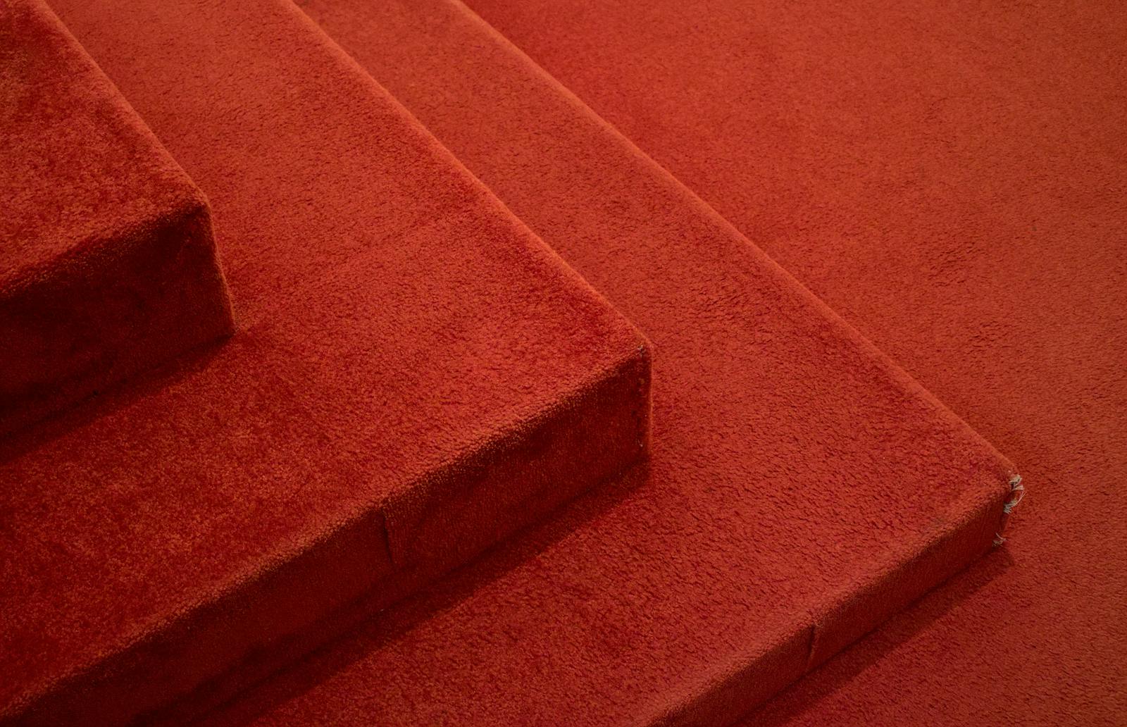 Detailed view of red carpeted stairs, highlighting texture and design.