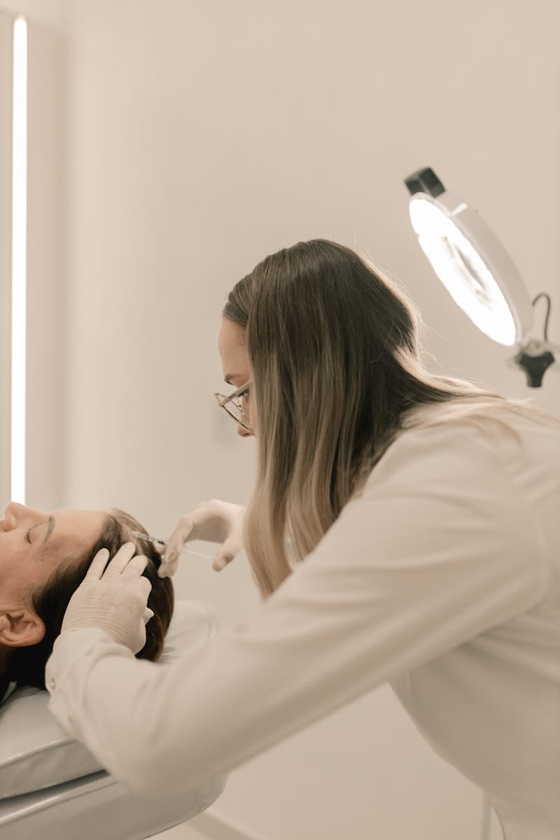 Dermatologist performing a treatment in a clinic setting with specialized equipment.