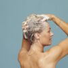 Woman shampooing her hair, showing a personal care routine with soap suds.