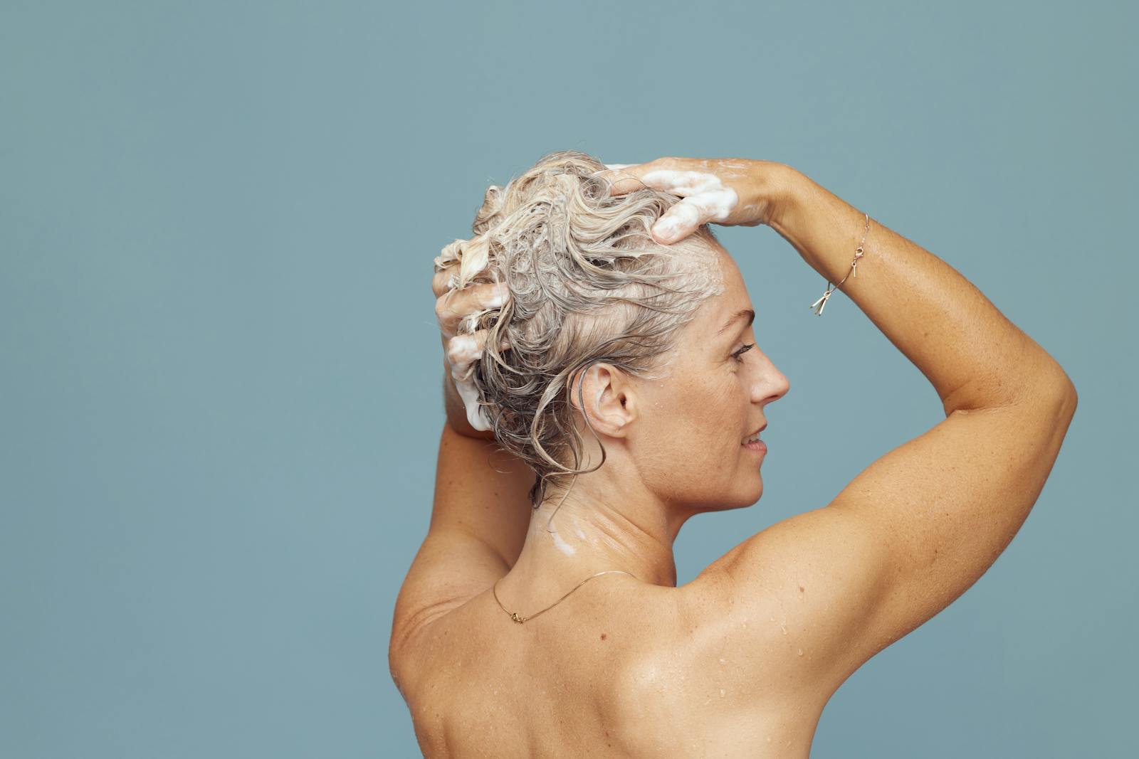 Woman shampooing her hair, showing a personal care routine with soap suds.
