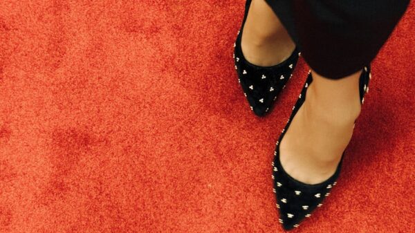 Black high heel shoes with studded design on vibrant red carpet. Fashion statement.