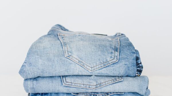 Pile of denim pants of different shades of blue placed on white shelf