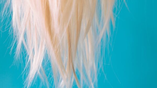 Close-up of blonde hair hanging against a light blue backdrop, creating a striking contrast.