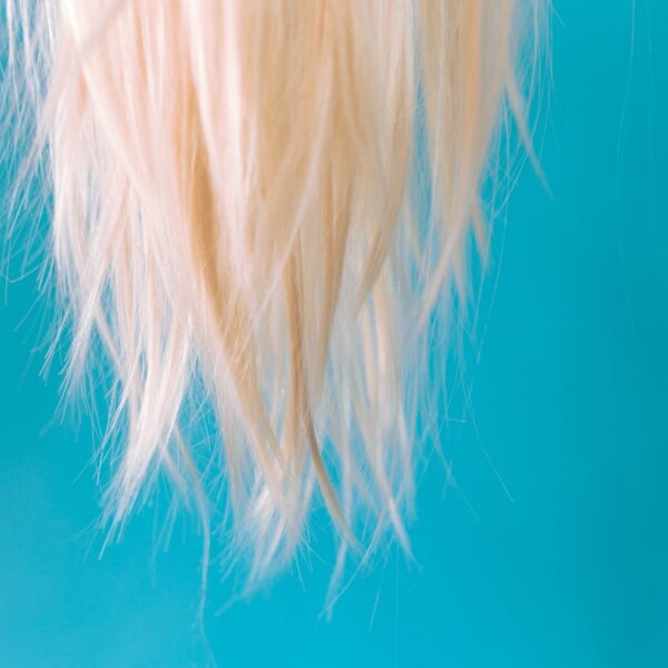 Close-up of blonde hair hanging against a light blue backdrop, creating a striking contrast.