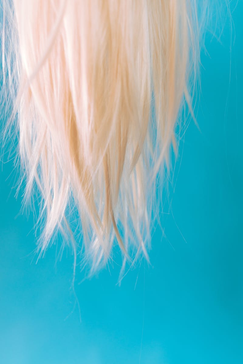 Close-up of blonde hair hanging against a light blue backdrop, creating a striking contrast.