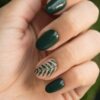 Close-up of a stylish green manicure with a leaf design, showcasing glossy fingernails and natural skin tone.