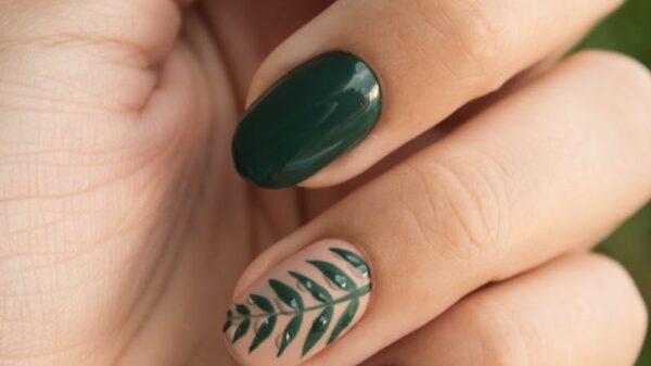 Close-up of a stylish green manicure with a leaf design, showcasing glossy fingernails and natural skin tone.