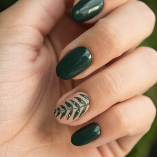 Close-up of a stylish green manicure with a leaf design, showcasing glossy fingernails and natural skin tone.