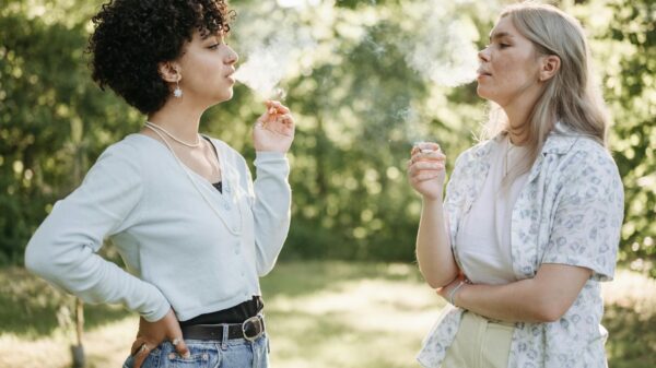 Two women smoking and conversing in a lush green outdoor setting, enjoying a moment of relaxation.