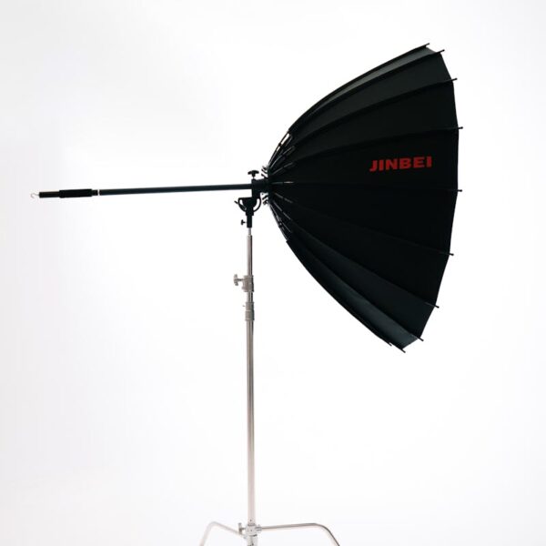 Black and silver Jinbei studio lighting umbrella on a stand for professional photography.