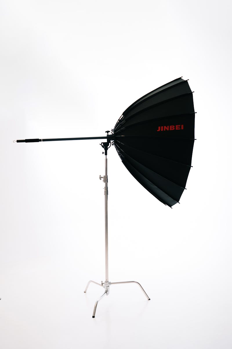 Black and silver Jinbei studio lighting umbrella on a stand for professional photography.