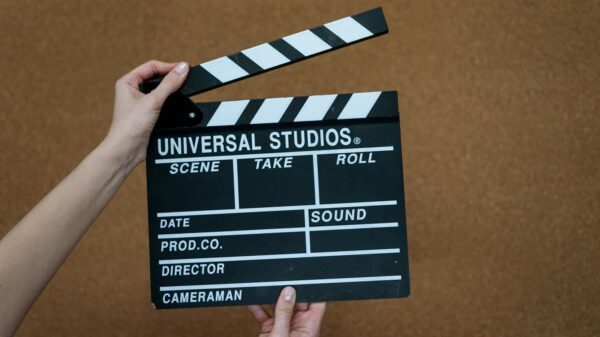 Close-up of hands holding a Universal Studios clapboard on a cork backdrop, ready for filming.