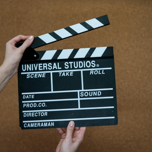 Close-up of hands holding a Universal Studios clapboard on a cork backdrop, ready for filming.