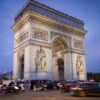 Iconic Arc de Triomphe under blue evening sky with bustling traffic in Paris.