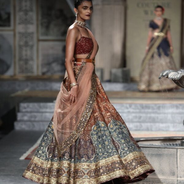 Model showcasing a traditional Indian lehenga on the runway at India Couture Week in New Delhi.