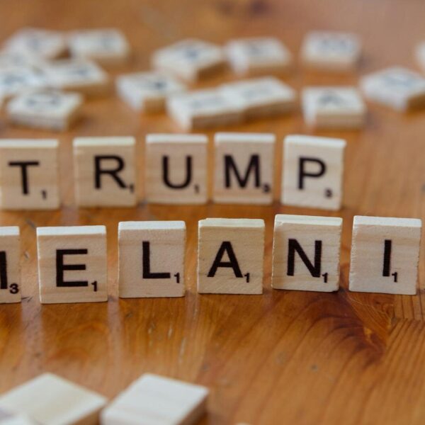 Wooden tiles arranged with letters spelling 'TRUMP' and 'MELANIA' on a table.