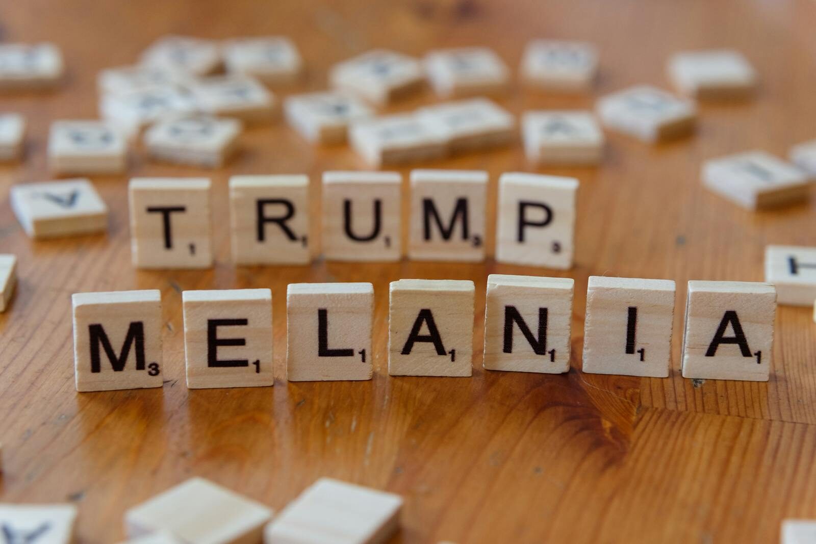 Wooden tiles arranged with letters spelling 'TRUMP' and 'MELANIA' on a table.