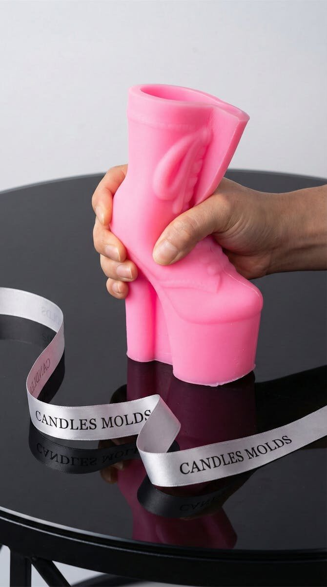 Pink high heel silicone candle mold held by hand on black table in New York. Perfect for creative candle making.
