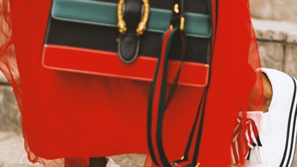 Fashionable woman in red dress with stylish bag and shoes on stairs.
