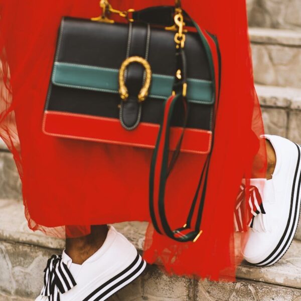 Fashionable woman in red dress with stylish bag and shoes on stairs.