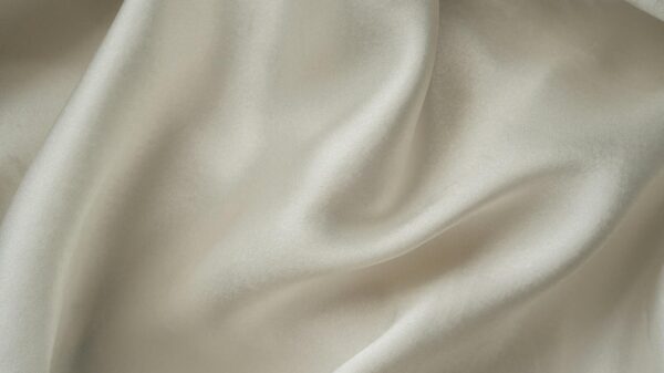 Close-up of smooth white silk fabric with soft folds and gentle draping.