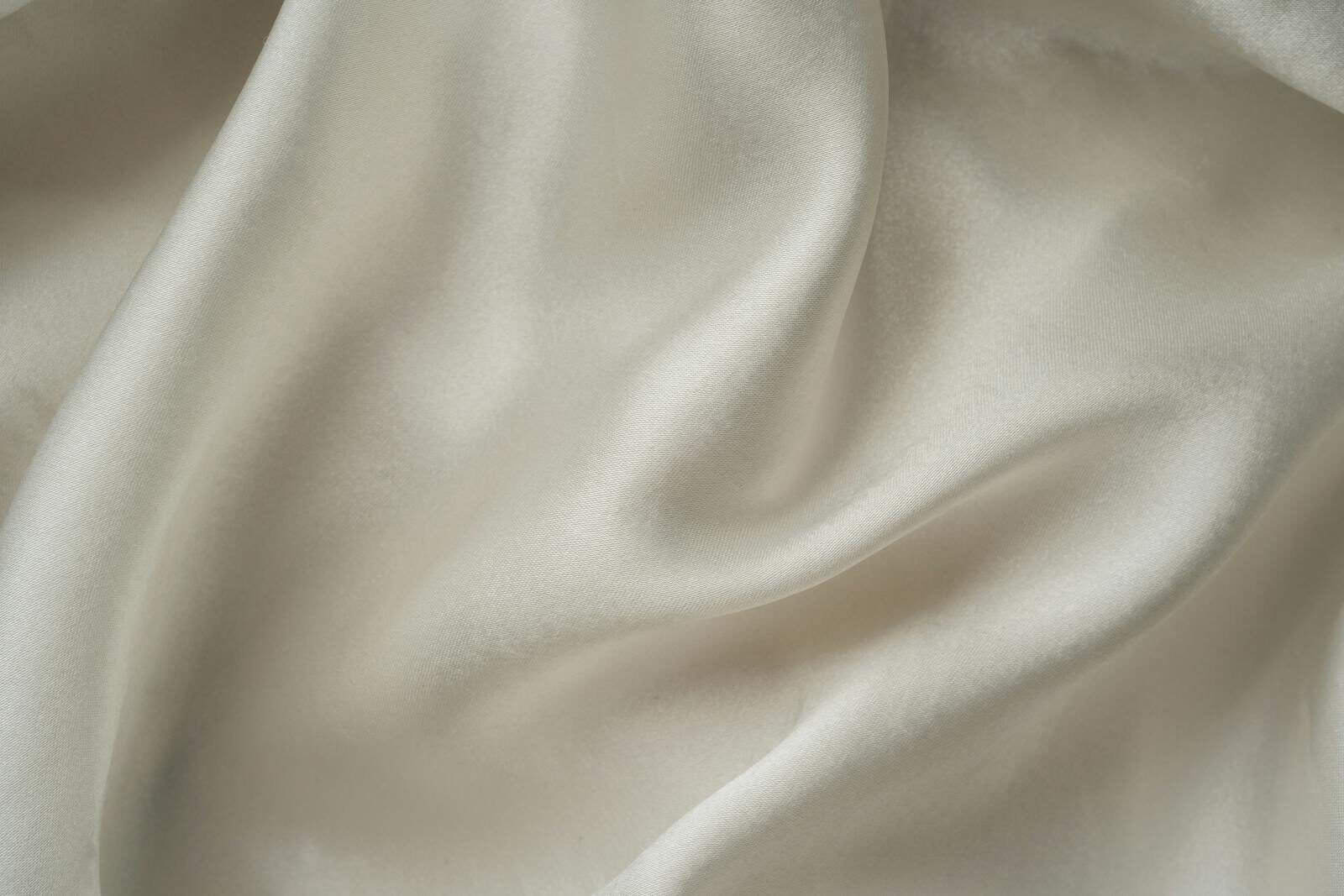 Close-up of smooth white silk fabric with soft folds and gentle draping.