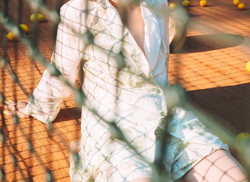 a woman sitting on a tennis court next to a net