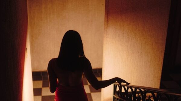 Woman in red dress walks down checkered stairs