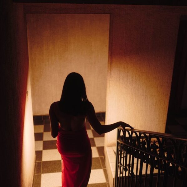 Woman in red dress walks down checkered stairs