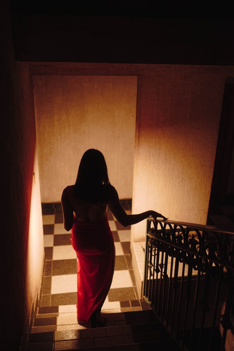 Woman in red dress walks down checkered stairs