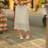 Woman in polka dot skirt standing by souvenir stand.