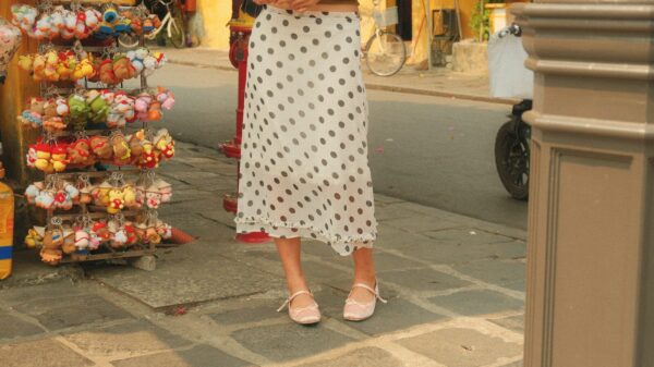 Woman in polka dot skirt standing by souvenir stand.