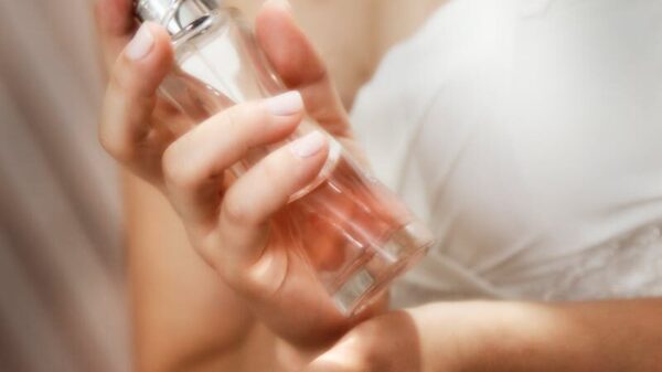 An elegant bride in a white gown applying perfume, capturing a moment of grace and preparation.