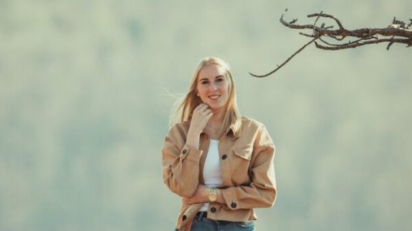 woman in pink long sleeve shirt and blue denim jeans standing on tree branch during daytime