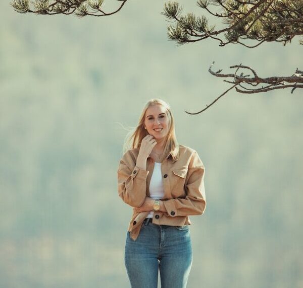 woman in pink long sleeve shirt and blue denim jeans standing on tree branch during daytime