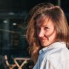 a woman in a white shirt is smiling at the camera